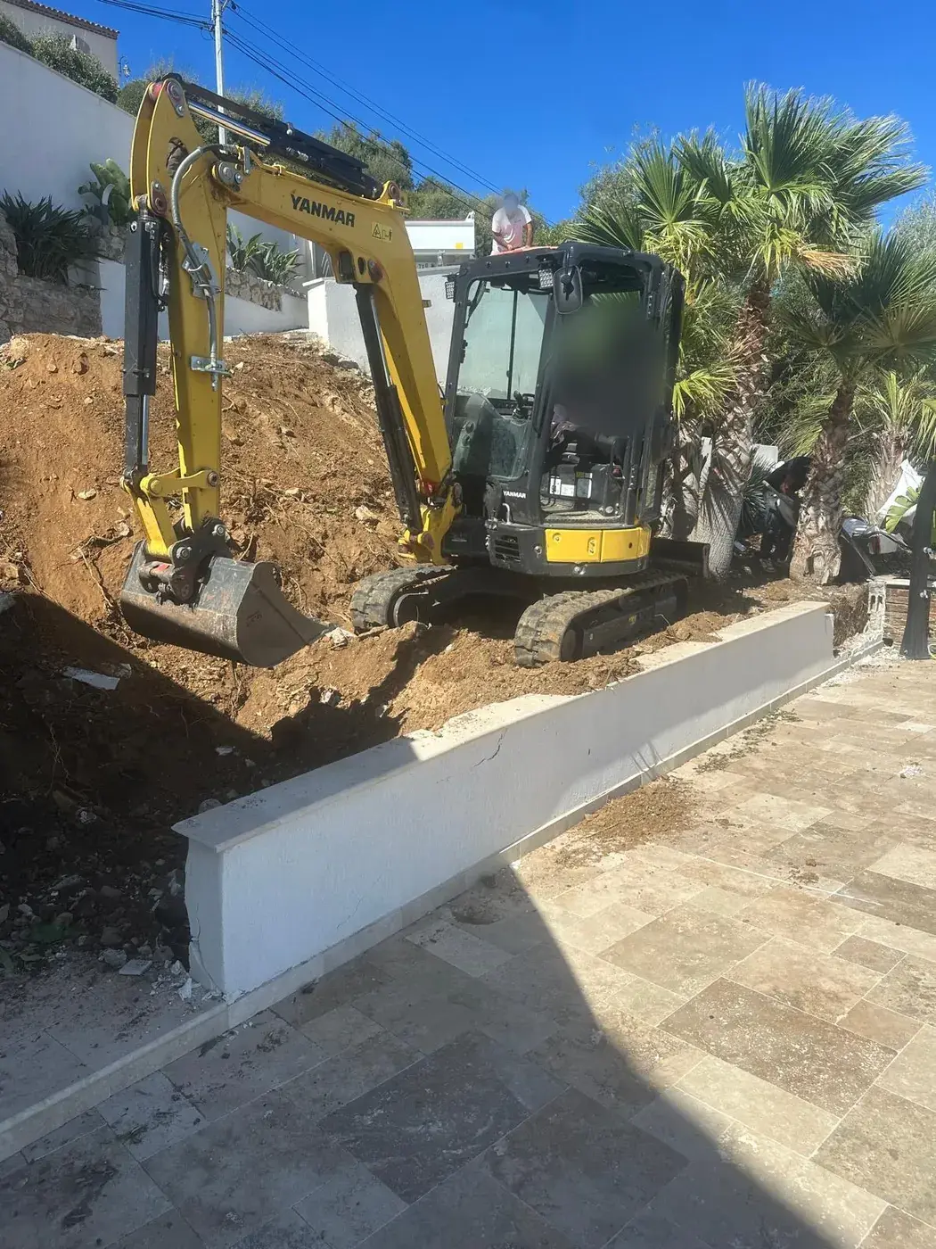 Mini-pelle en cours de terrassement au pied du mur de soutènement