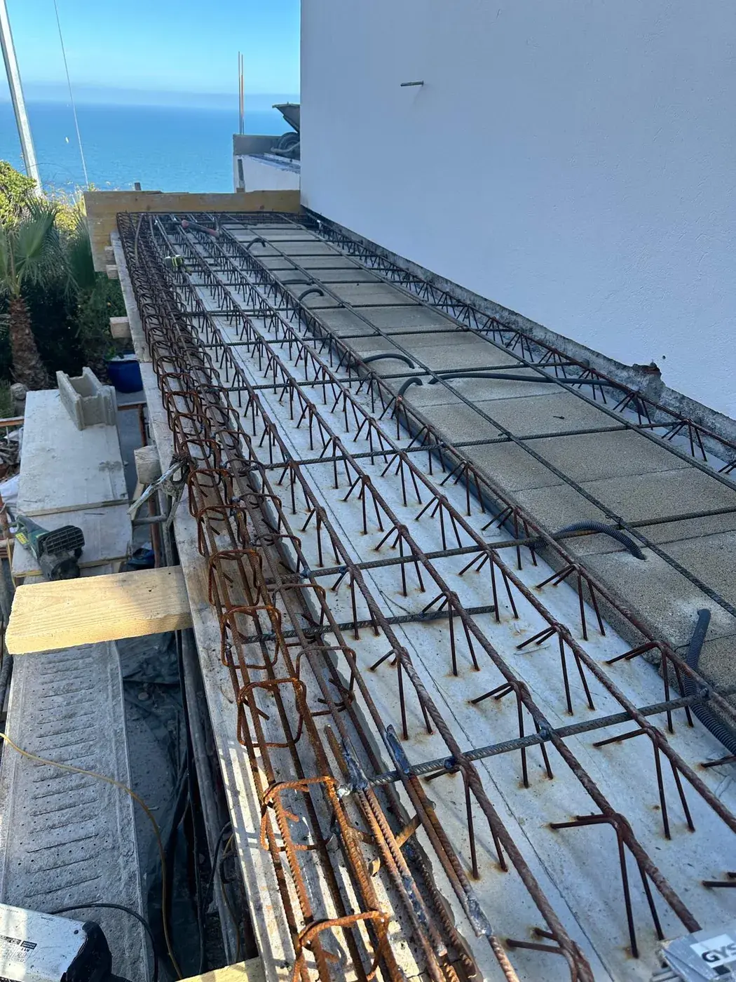 Poutres béton armé ferraillées en attente de coulage, vue sur la mer
