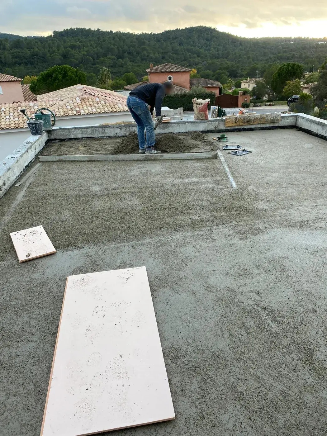 Chape en cours sur le toit-terrasse, collines boisées au fond