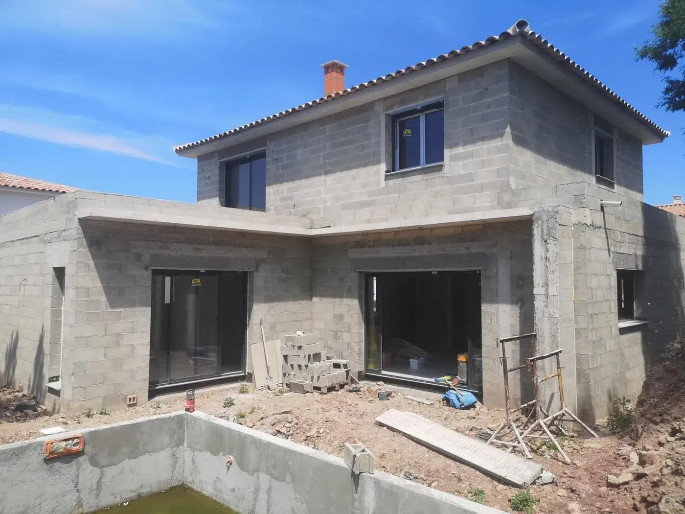 La même maison en parpaings avant enduit, piscine en construction