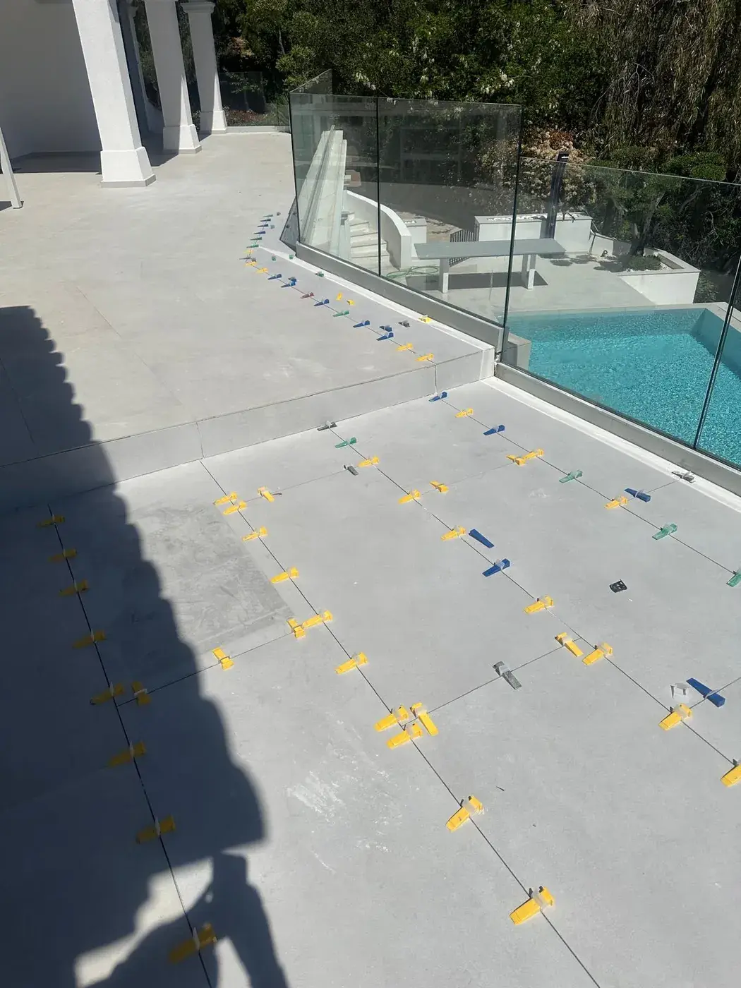 Dalles grand format calées avec croisillons autour de la piscine
