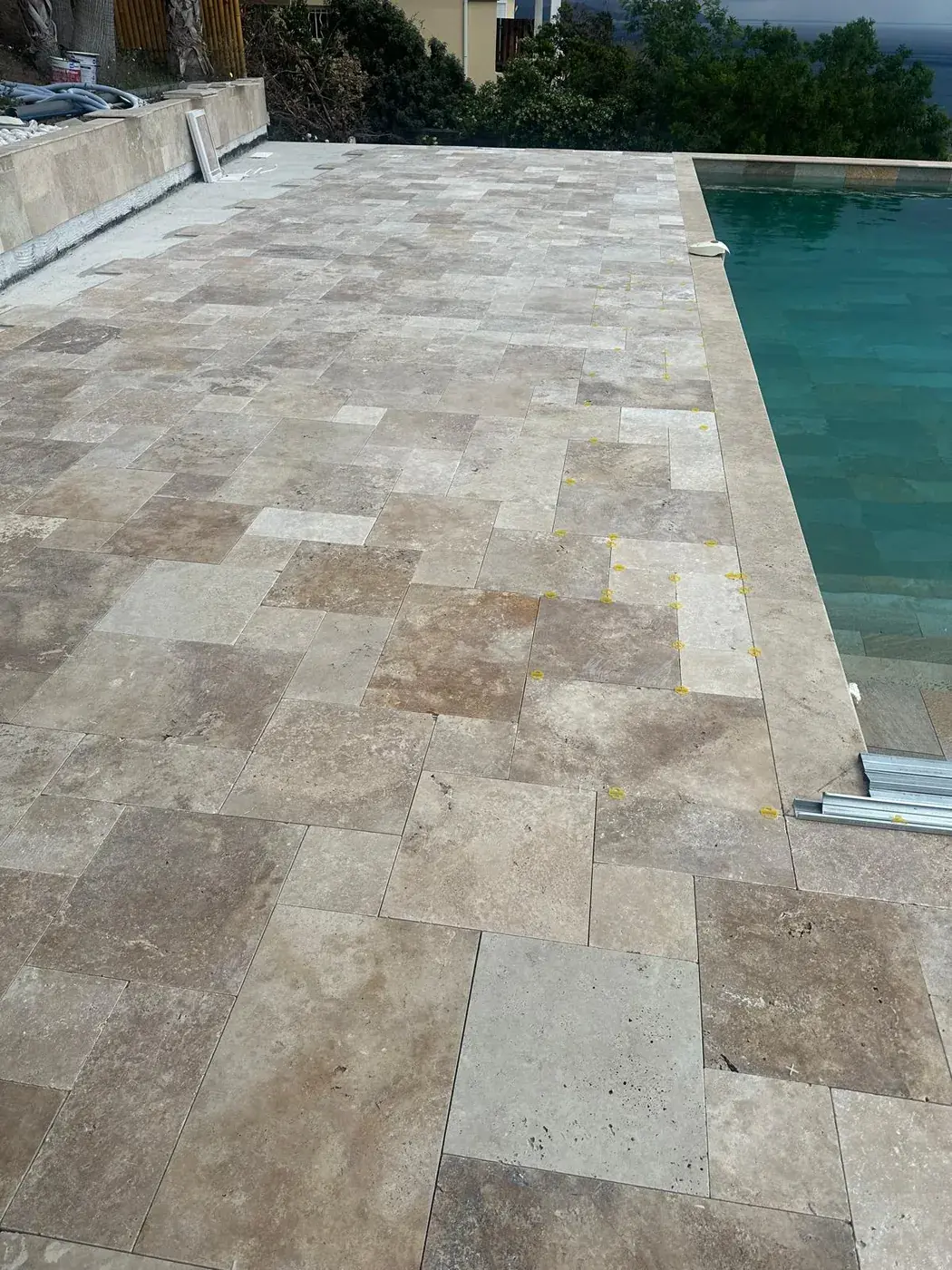 Margelles et plage de piscine en travertin vues depuis le bassin