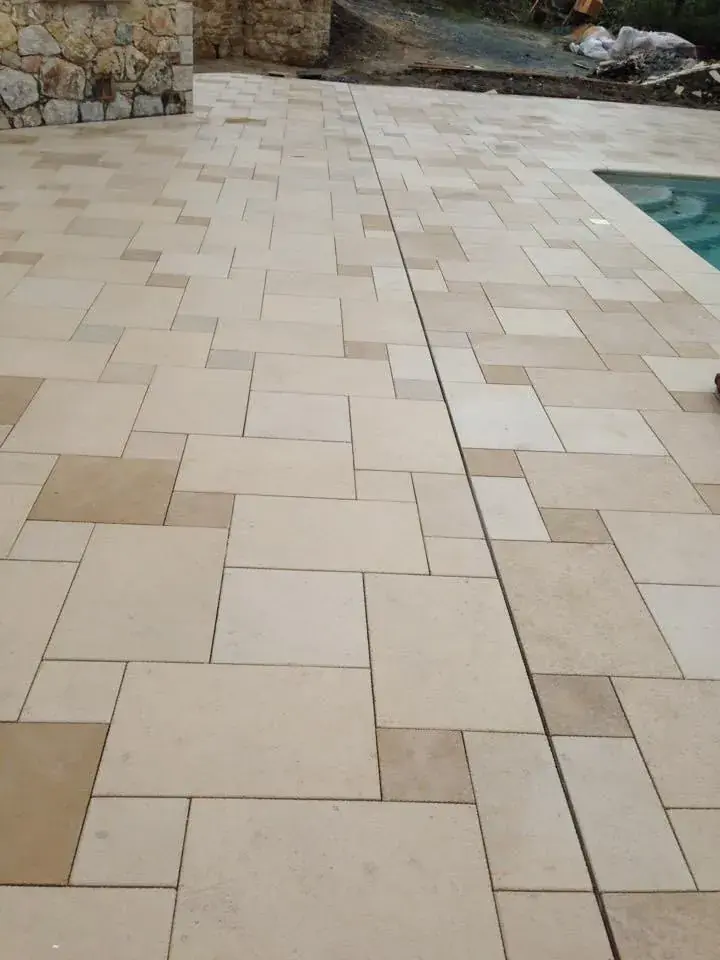 Plage de piscine en pierre claire, mur en pierre sèche