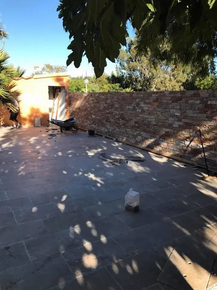 Terrasse en dalles sombres le long d'un mur en pierre
