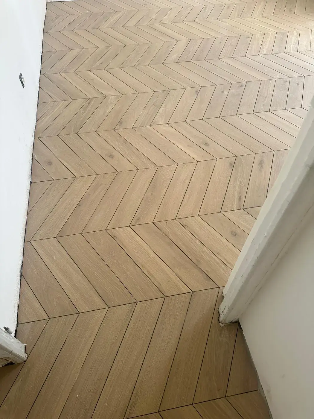 Carrelage effet parquet posé en chevron dans un couloir