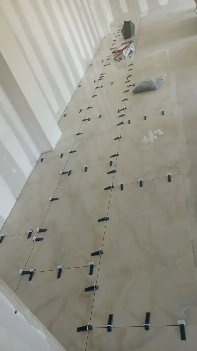 Grand format en cours de pose le long d'un mur, croisillons en place