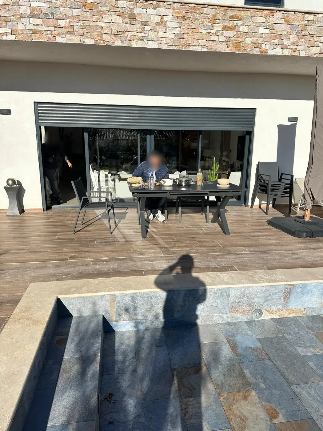 Terrasse en pierre naturelle prolongée par une plateforme bois au-dessus de la piscine