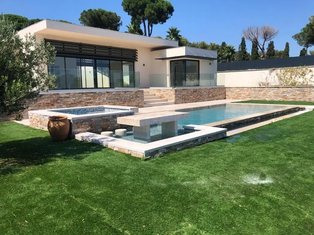 Piscine avec spa surélevé et banc, devant une villa contemporaine