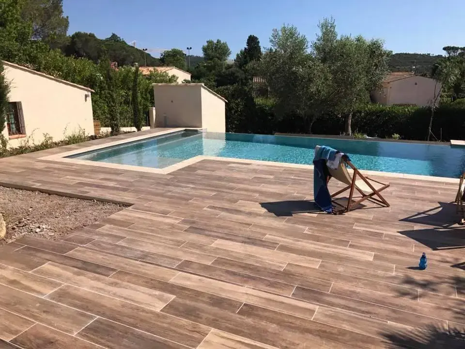 Plage de piscine en grès effet bois et jardin méditerranéen