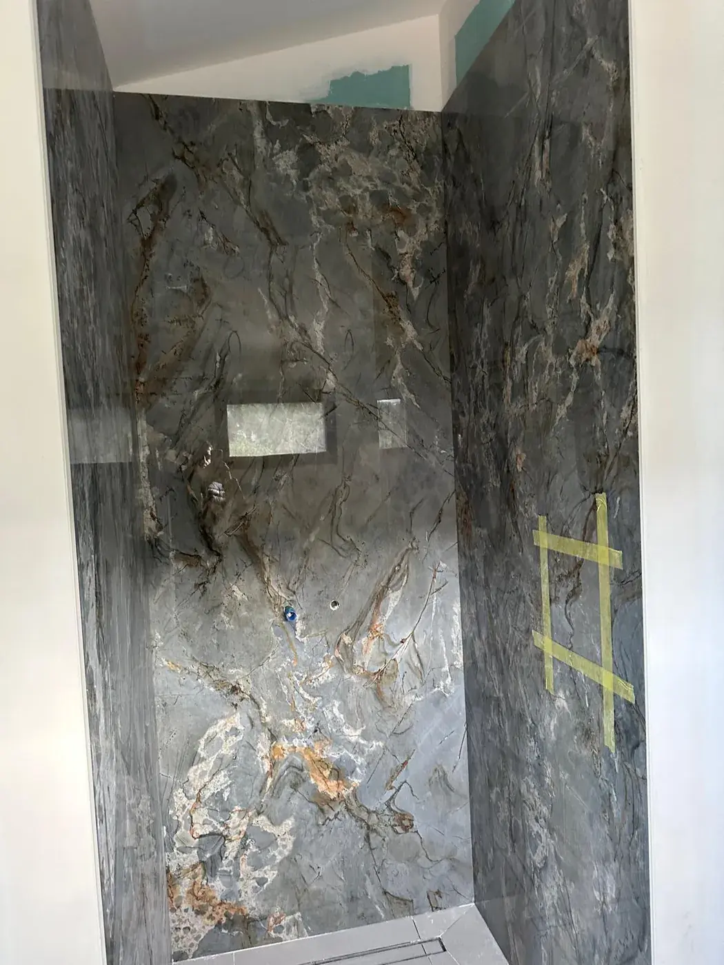 Paroi de douche habillée de marbre veiné en raccord de veinage