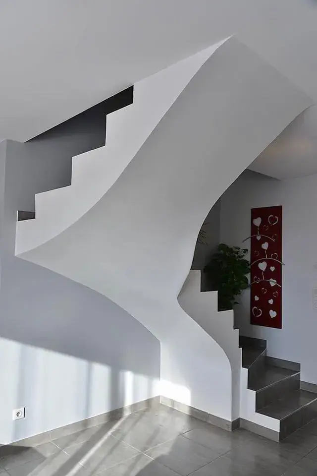 Escalier béton à limon courbe, enduit et poncé, dans un séjour